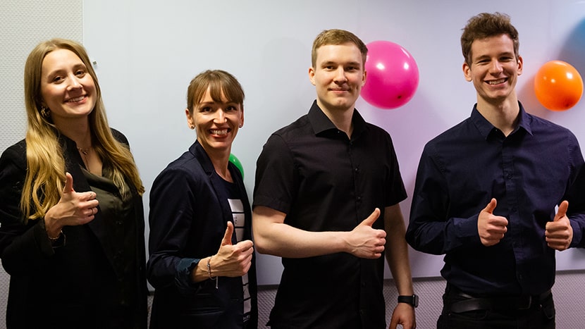 Die vier Teammitglieder Maria, Marie, Clemens und Simon lächeln in die Kamera und strecken die Daumen raus